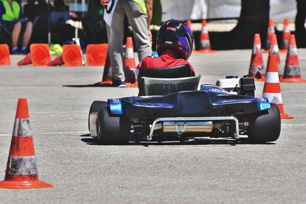 Pilote en kart bleu sur circuit avec cônes oranges