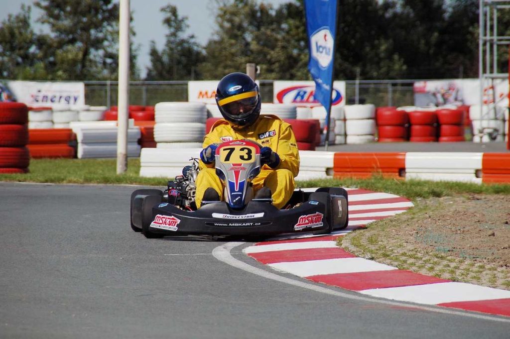Pilote de kart en virage, portant le numéro 73, sur un circuit de course automobile
