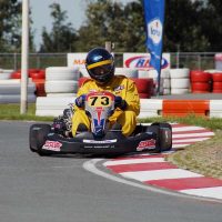 Pilote de kart en virage, portant le numéro 73, sur un circuit de course automobile
