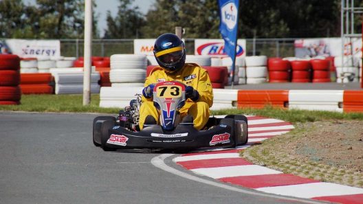 Pilote de kart en virage, portant le numéro 73, sur un circuit de course automobile