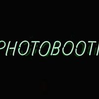 a neon sign that reads photo booth on a dark background