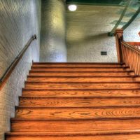 Un escalier en bois avec main-courante et éclairage dans un couloir en brique