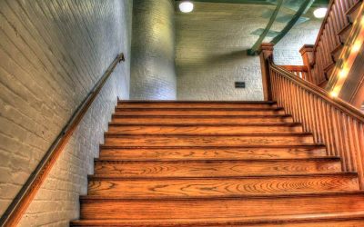 Un escalier en bois avec main-courante et éclairage dans un couloir en brique