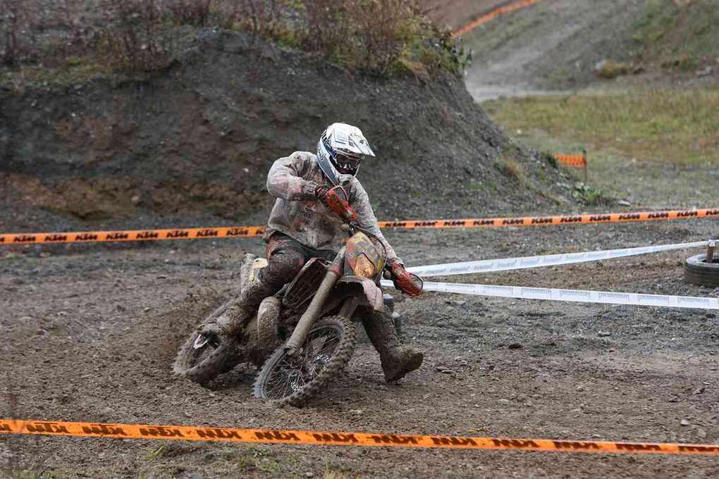 Motocycliste en action sur un circuit boueux, équipé de barrières de sécurité Motocycliste en action sur un circuit boueux, équipé de barrières de sécurité