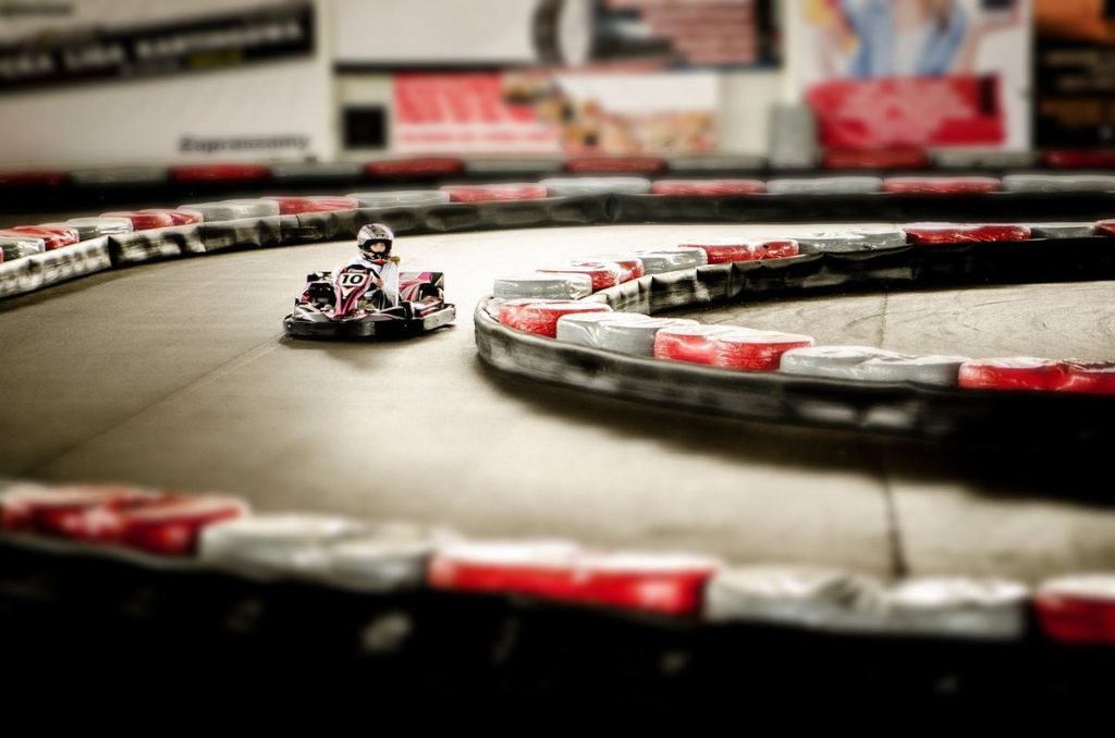 Un kart miniature tourne sur un circuit intérieur bordé de barrières