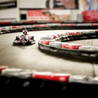 Un kart miniature tourne sur un circuit intérieur bordé de barrières
