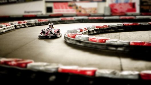 Un kart miniature tourne sur un circuit intérieur bordé de barrières